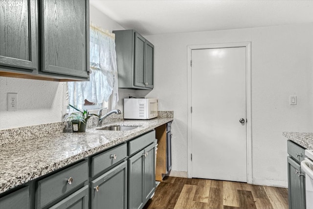 kitchen with light stone countertops, dark hardwood / wood-style flooring, gray cabinets, and sink