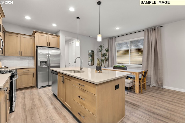 kitchen with light wood-type flooring, appliances with stainless steel finishes, sink, and pendant lighting