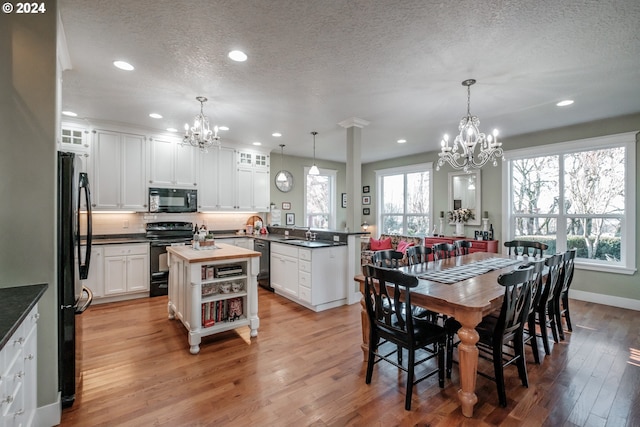 dining space featuring a textured ceiling, light wood-type flooring, and a notable chandelier