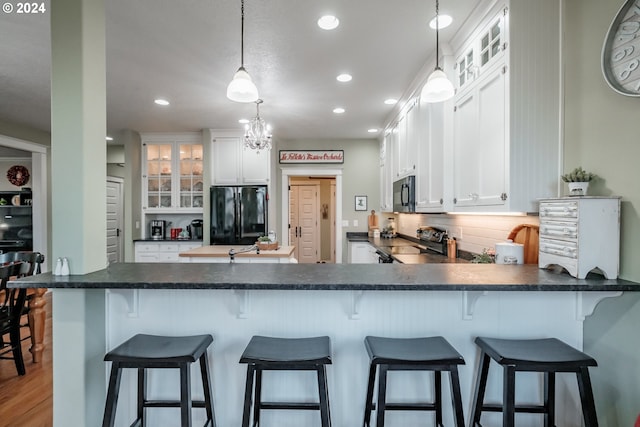 kitchen with kitchen peninsula, white cabinetry, and black appliances