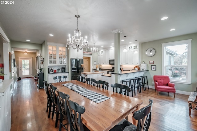 dining room featuring a wealth of natural light, a notable chandelier, and light wood-type flooring