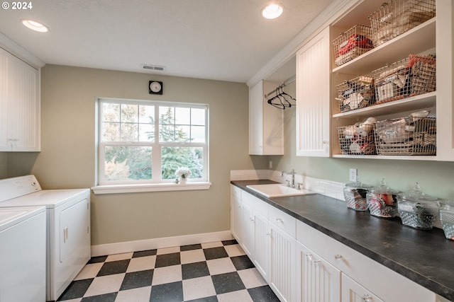 laundry room featuring washing machine and clothes dryer, sink, and cabinets