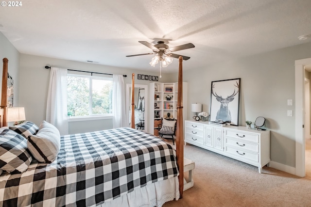 bedroom featuring a textured ceiling, light colored carpet, and ceiling fan