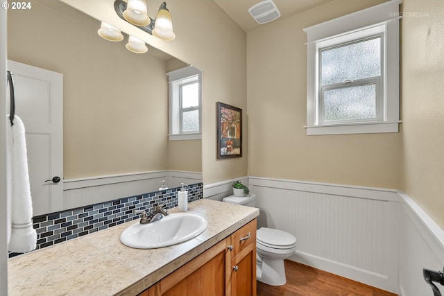 bathroom with hardwood / wood-style flooring, toilet, tasteful backsplash, and vanity