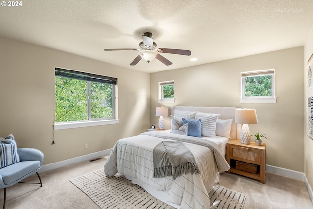 bedroom with multiple windows, ceiling fan, and light colored carpet