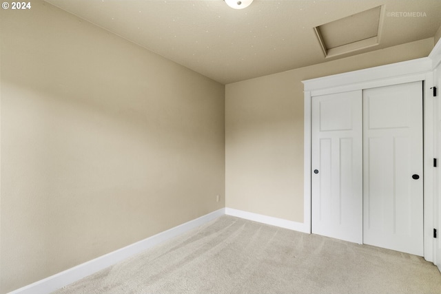 unfurnished bedroom with a closet and light colored carpet