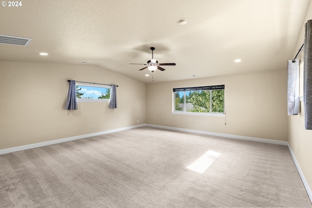 carpeted empty room with a textured ceiling, a healthy amount of sunlight, ceiling fan, and lofted ceiling