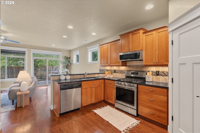 kitchen featuring dark hardwood / wood-style flooring, ceiling fan, appliances with stainless steel finishes, decorative backsplash, and sink