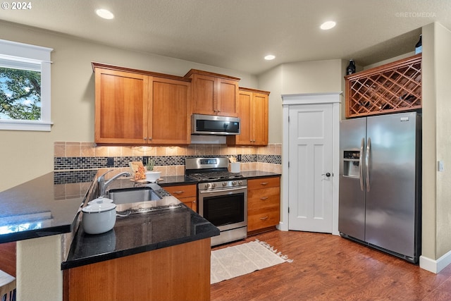 kitchen featuring sink, appliances with stainless steel finishes, kitchen peninsula, and hardwood / wood-style floors