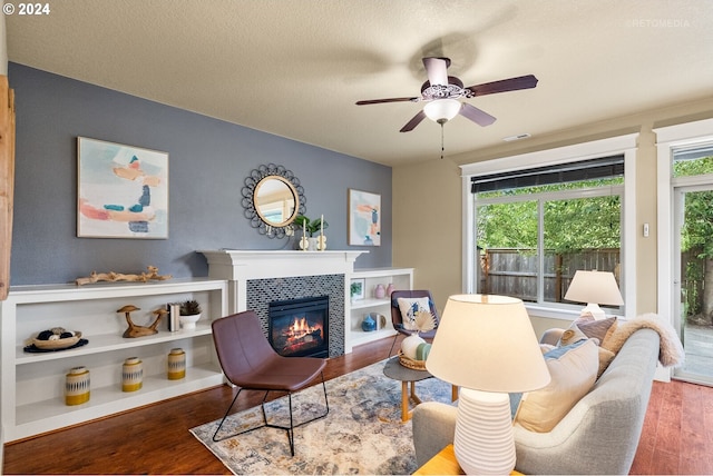 living room featuring a fireplace, a textured ceiling, ceiling fan, and hardwood / wood-style floors