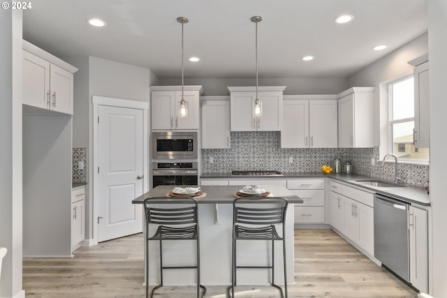 kitchen with stainless steel appliances, a center island, sink, and white cabinets