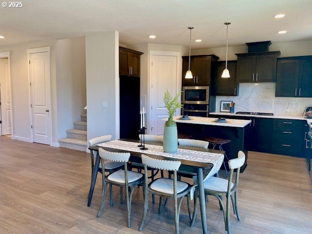 dining room featuring recessed lighting, light wood-type flooring, and stairs