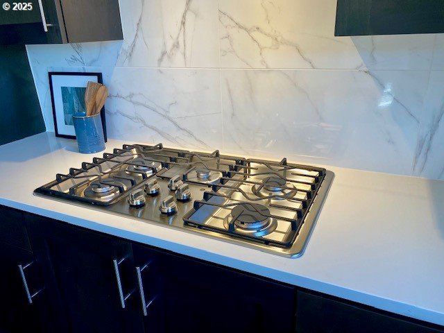 interior details featuring light countertops, tasteful backsplash, and stainless steel gas cooktop