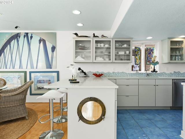 kitchen featuring a breakfast bar, sink, stainless steel dishwasher, tile floors, and kitchen peninsula