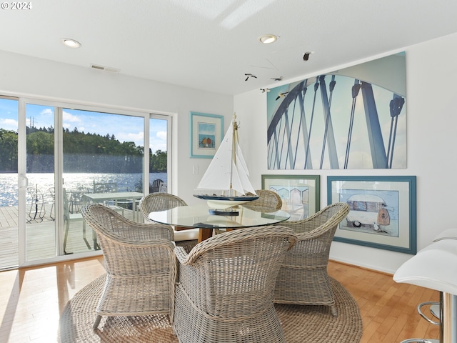 dining space featuring light hardwood / wood-style floors and a water view