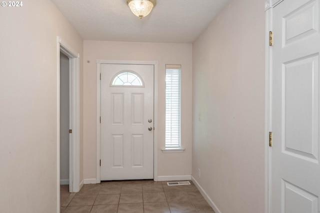 entryway featuring a textured ceiling, plenty of natural light, and light tile patterned floors