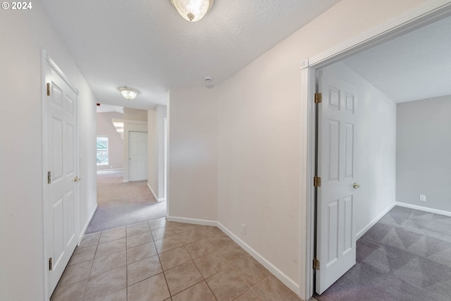 corridor featuring light colored carpet and a textured ceiling