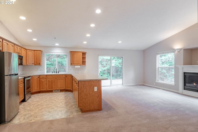 kitchen with stainless steel appliances, lofted ceiling, light carpet, and plenty of natural light