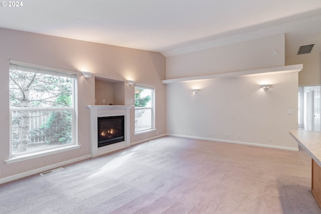 unfurnished living room with lofted ceiling and light carpet