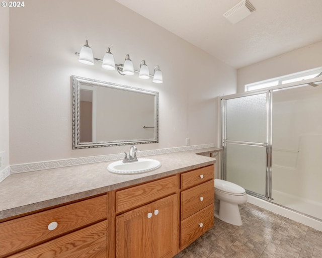 bathroom with walk in shower, vanity, and toilet