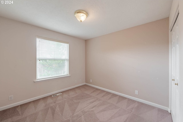 carpeted empty room featuring a textured ceiling