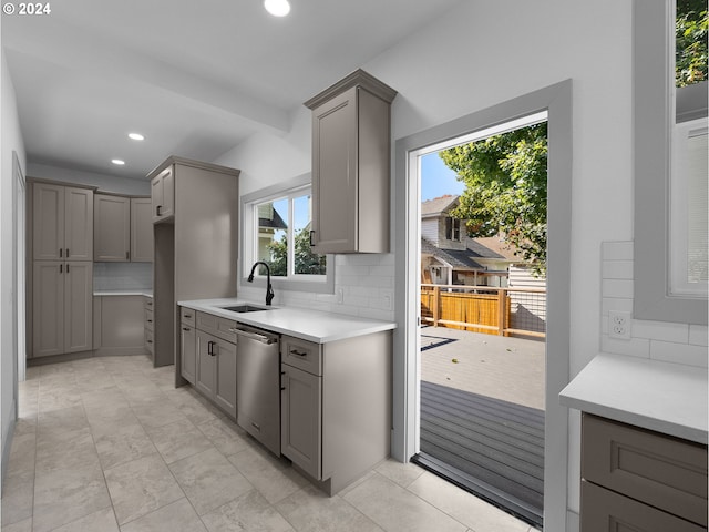 kitchen featuring sink, tasteful backsplash, dishwasher, and gray cabinetry