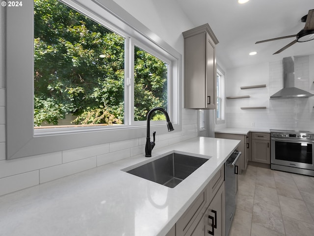 kitchen featuring tasteful backsplash, appliances with stainless steel finishes, sink, wall chimney exhaust hood, and gray cabinets