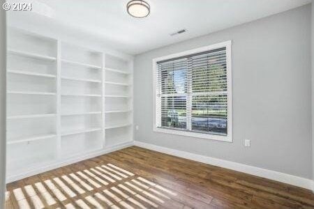 empty room featuring built in features and hardwood / wood-style flooring