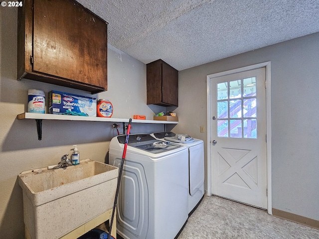 clothes washing area featuring light tile floors, sink, a textured ceiling, separate washer and dryer, and cabinets