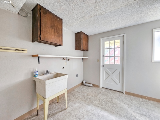 laundry room with hookup for an electric dryer, a textured ceiling, cabinets, and light tile floors