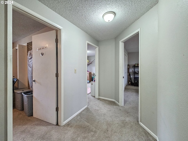 hall featuring light colored carpet and a textured ceiling