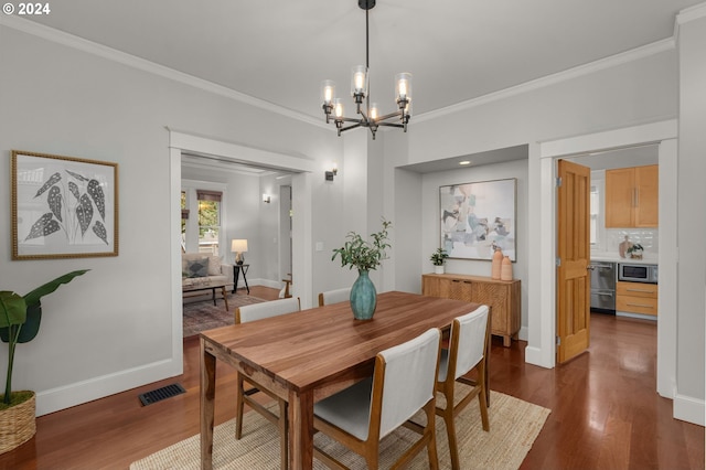 dining area featuring an inviting chandelier, ornamental molding, and dark hardwood / wood-style flooring