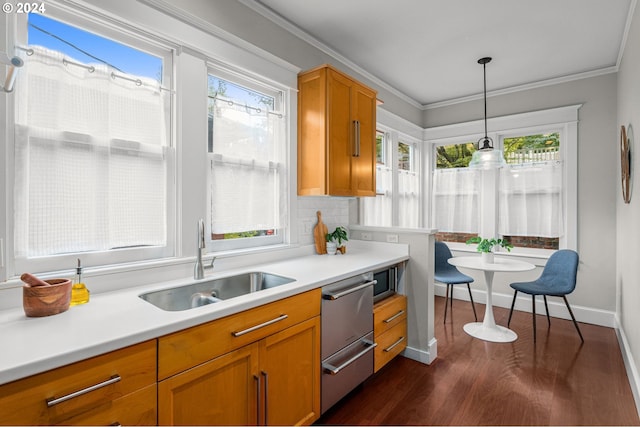 kitchen with crown molding, decorative light fixtures, sink, and dark wood-type flooring