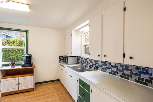 kitchen featuring sink, white cabinets, tasteful backsplash, and light hardwood / wood-style flooring