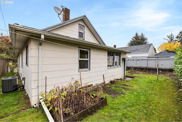 view of side of home featuring central air condition unit and a yard