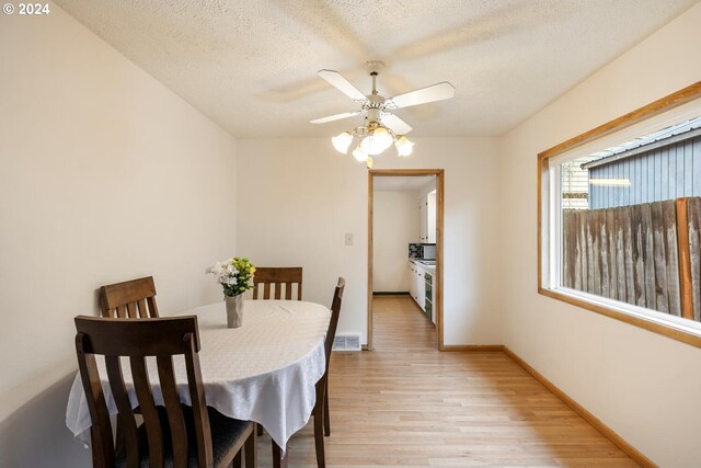 dining area featuring light wood-type flooring, ceiling fan, and a textured ceiling