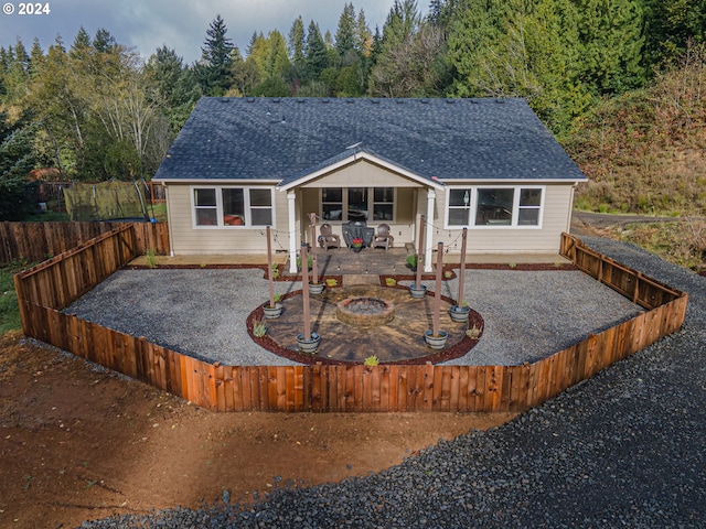 1843 Shelley Rd, Coquille, OR 97423 - rear view of house featuring a shingled roof, a fenced backyard, a fire pit, a patio, and a view of trees