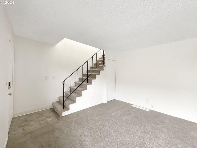 interior space featuring a textured ceiling and carpet floors