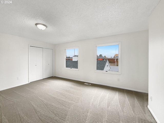 unfurnished bedroom featuring dark colored carpet, a textured ceiling, and a closet