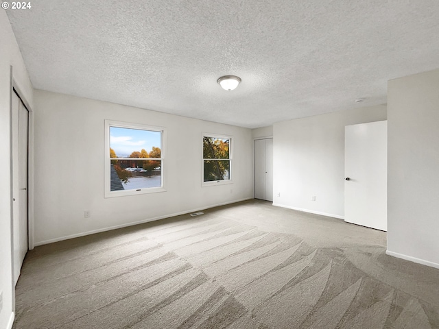 carpeted empty room with a textured ceiling