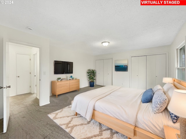 bedroom featuring carpet, multiple closets, and a textured ceiling