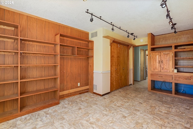 unfurnished bedroom with a textured ceiling and wood walls