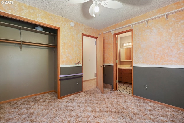 unfurnished bedroom featuring ceiling fan, light colored carpet, a textured ceiling, and a closet