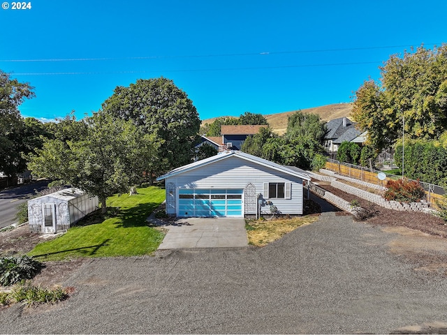 view of front of property featuring a garage, a front yard, and a storage shed