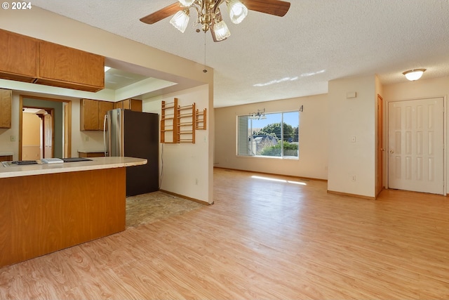 kitchen featuring light wood-type flooring, a textured ceiling, stainless steel refrigerator, and gas cooktop