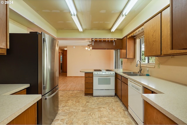 kitchen featuring white appliances, kitchen peninsula, and sink