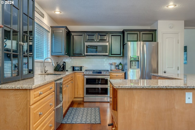 kitchen featuring light stone countertops, hardwood / wood-style flooring, stainless steel appliances, and a textured ceiling