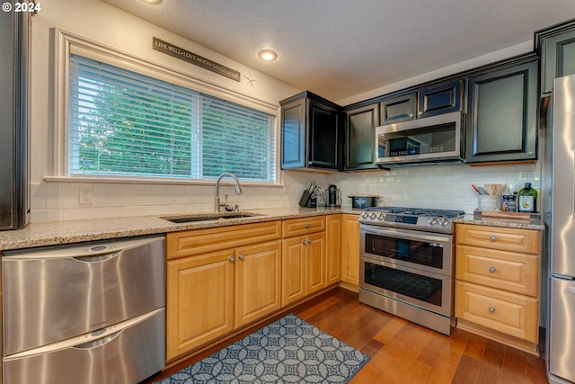 kitchen featuring light stone countertops, stainless steel appliances, dark wood-type flooring, and a healthy amount of sunlight