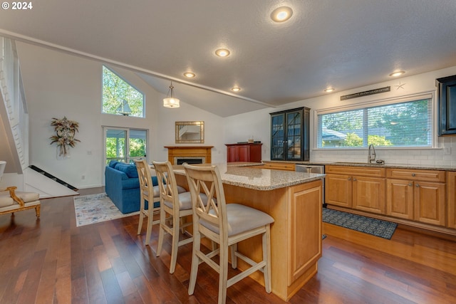 kitchen with hanging light fixtures, tasteful backsplash, dark hardwood / wood-style flooring, a kitchen bar, and a center island