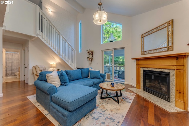 living room featuring a towering ceiling, beamed ceiling, a fireplace, and dark hardwood / wood-style floors